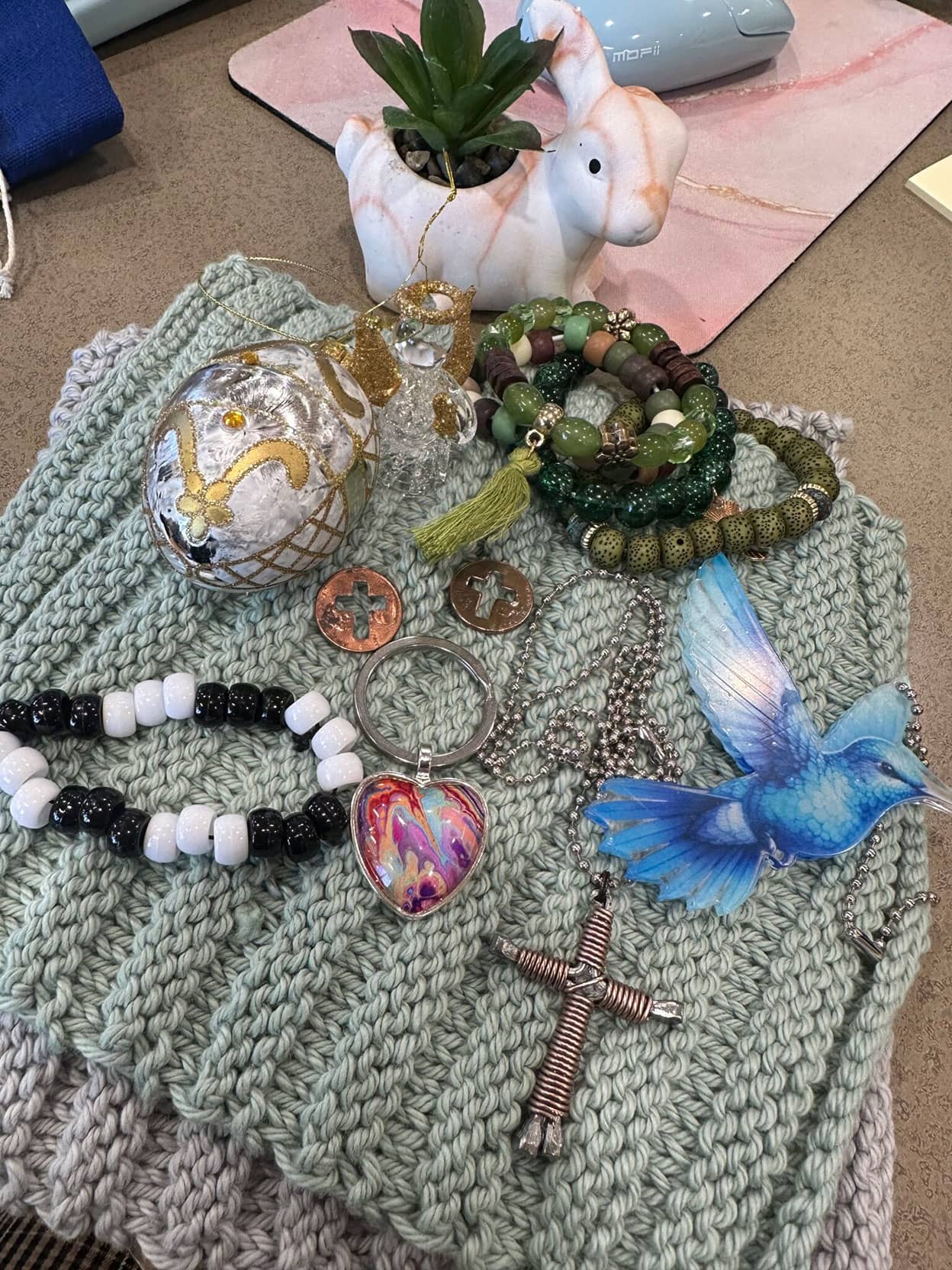 Recuerdos, que incluyen pulseras de cuentas hechas a mano, un salvamanteles de crochet y llaveros, colocados sobre un escritorio.