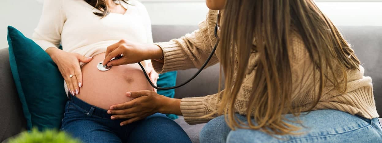 Provider applying a stethoscope to a pregnant belly