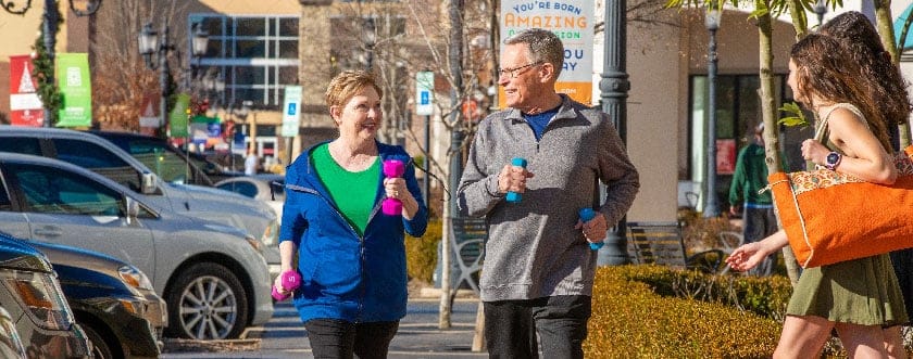 Seniors walking together and holding light dumbbells