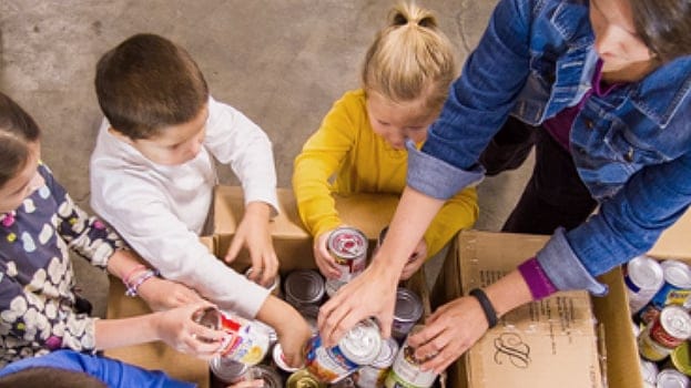 Adult and children placing canned goods into a box