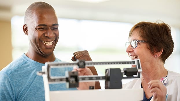 Smiling man being weighed by happy provider
